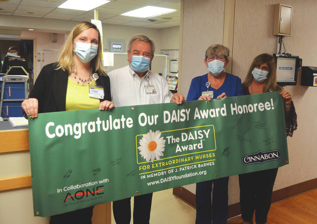 Wayne HealthCare RN and Charge Nurse Deb Osborne was presented with the DAISY Award Wednesday. Holding the banner she was presented with (from left) are VP of Patient Care Services and Chief Nursing Officer Kim Freeman, CEO Wayne Deschambeau, Osborne and Sharlyn Hickey.